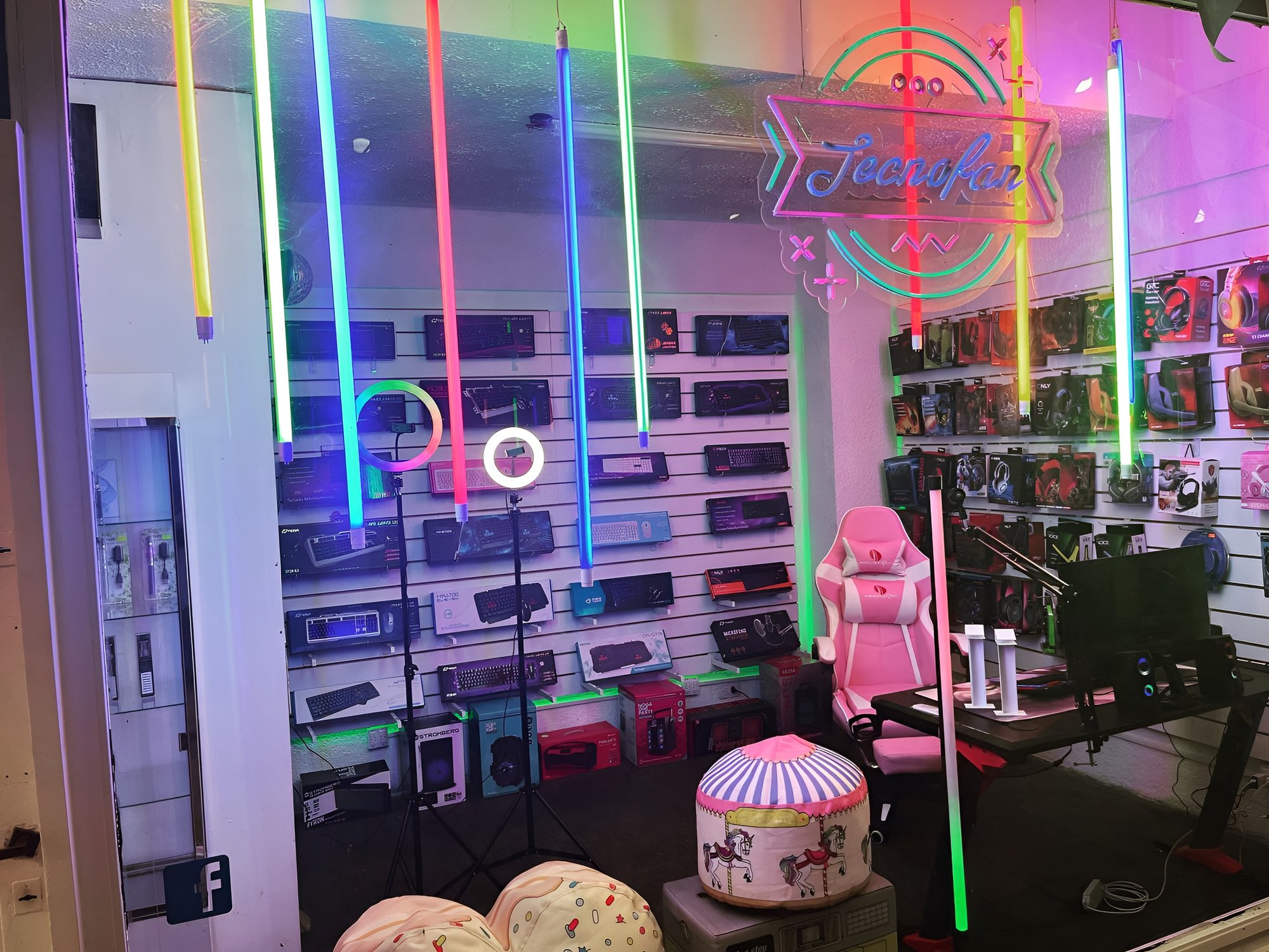 Showroom del Local 19: pared de teclados y auriculares, silla gamer rosa y escritorio con monitor